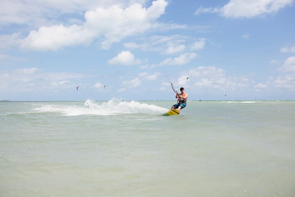 Imagem mostra jovem praticando kitesurf em praia pernambucana.