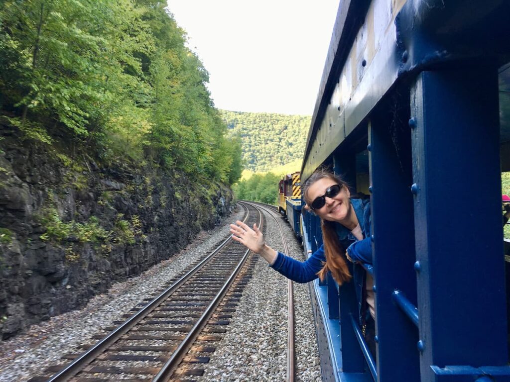 Imagem mostra mulher feliz viajando de trem.