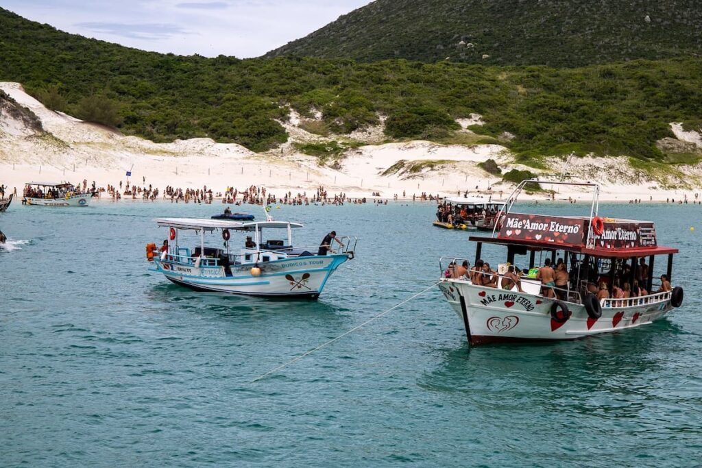 Imagem mostra grupo de turistas e um dos passeios de barco em Arraial do Cabo.