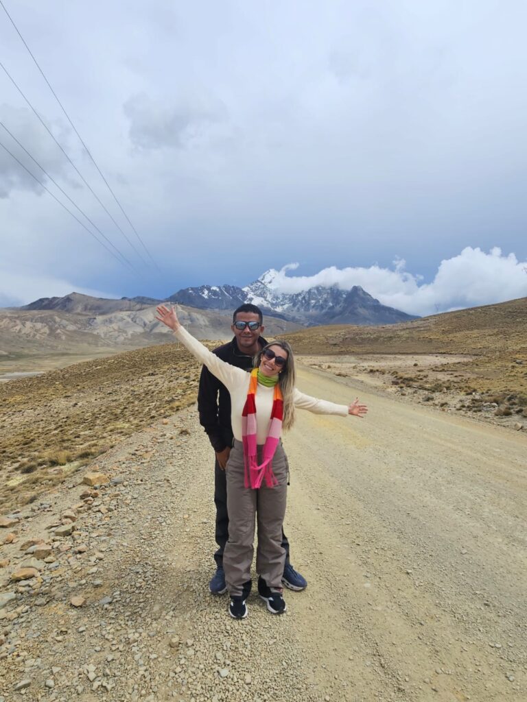 imagem mostra casal de turista tirando fotos no caminho até a base do Nevado de Charquine e Laguna Esmeralda.